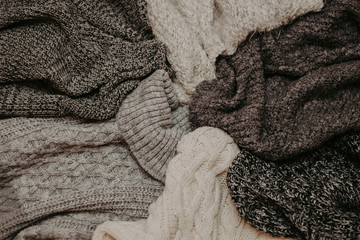 Fototapeta na wymiar Background with warm sweaters. Pile of knitted clothes, warm background, knitwear, space for text, autumn winter concept.