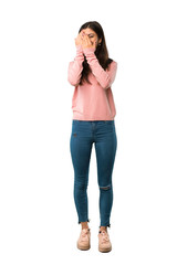 A full-length shot of a Teenager girl with pink shirt covering eyes by hands and looking through the fingers