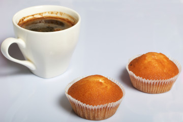 A cup of freshly brewed coffee and muffins. On a white background.