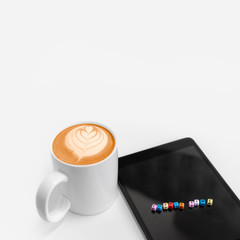 Hot coffee frothy drink with leaf art and tablet with letters coffee time cube blocks.