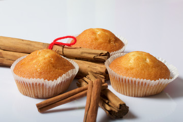 Fresh tasty muffins. Nearby are cinnamon sticks. On a white background.