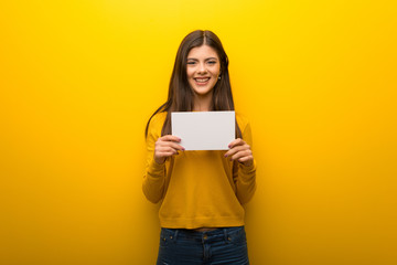 Teenager girl on vibrant yellow background holding a placard for insert a concept