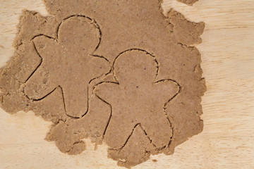 Two ginger men dough shapes on light wooden background. Cooking, Christmas, recipe, human design concept. Top view, copy space, flat lay, mock up, layout design