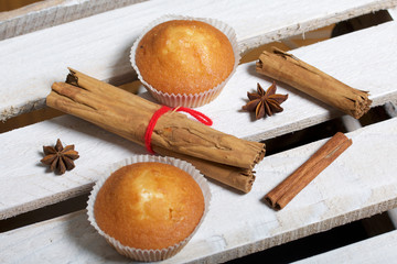 Fresh tasty muffins. Nearby are cinnamon sticks and anise stars. Located on a wooden box.