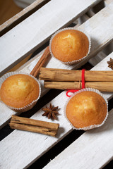 Fresh tasty muffins. Nearby are cinnamon sticks and anise stars. Located on a wooden box.