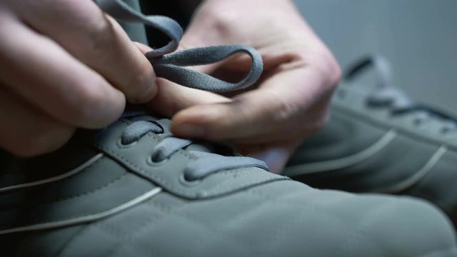 Man's hands tying laces on shoes for training. Close up 4k footage.