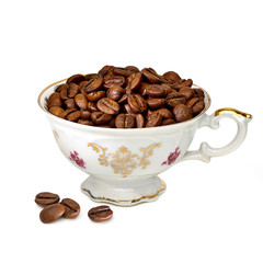 Heap of coffee beans in porcelain antique coffee cup isolated on white background.