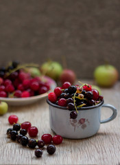  Assorted garden berries in a mug on a wooden background