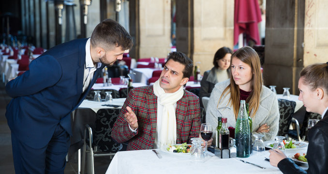 Angry guests with manager in restaurant