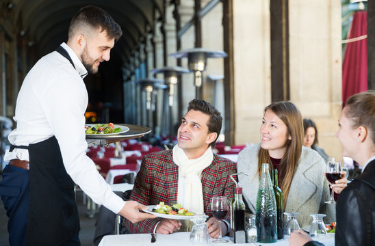 Waiter serving guests at terrace restaurant