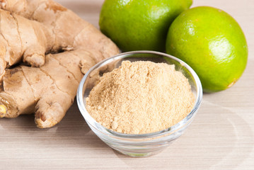 Ginger root and ginger powder on wooden background