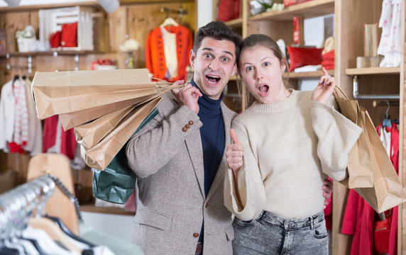 Smiling couple is satisfied of purchases and standing with package