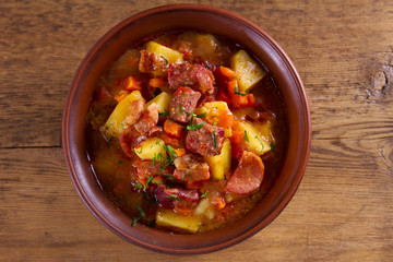 Goulash soup bograch in a bowl. Hungarian dish. Stew, made with beef, bacon, sausages, potatoes and carrots. View from above, top studio shot