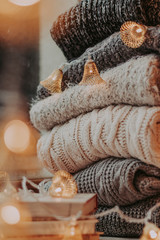 Home decor, sweaters, a stack of books and light bulbs, cozy winter interior details.