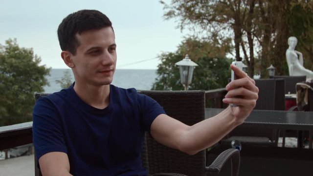 4K A handsom man makes selfie on smartphone.
