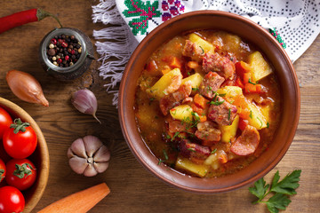 Goulash soup bograch in a bowl. Hungarian dish. Stew, made with beef, bacon, sausages, potatoes and carrots. View from above, top studio shot