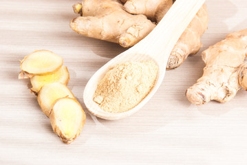 Ginger root and ginger powder on wooden background