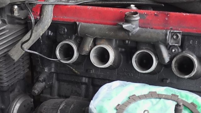 Part of old unusable motorcycle engine storing inside of old dirty garage. Slowly shift focus handheld slow-motion shot, 29.97fps.