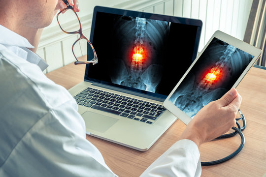 Doctor Watching X-ray Of Spine With Pain On A Laptop And A Digital Tablet