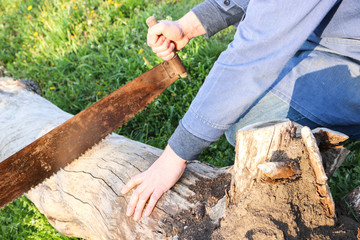 Man is cutting an old beam with a rusty saw.