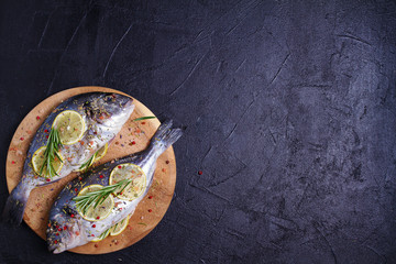 Sea bream or dorado  fish with lemon, herbs, vegetables and spices. Flatlay, overhead, copy space