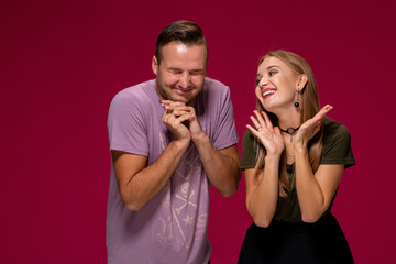 Girlfriend decided with her cute boyfriend to buy puppy. Indoor studio shot on burgundy background.