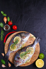 Sea bream or dorado  fish with lemon, herbs, vegetables and spices. Flatlay, overhead