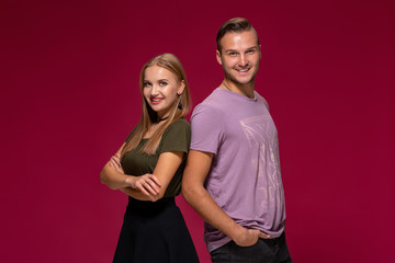 Young nice couple posing in the studio, express emotions and gestures, smiling, on a burgundy background