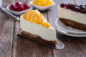 Cheesecake with peaches and cherries. filed on a wooden table with a silver spatula