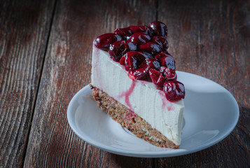 Cheesecake with peaches and cherries. filed on a wooden table with a silver spatula
