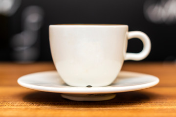 Coffee cup on wooden table with bokeh background