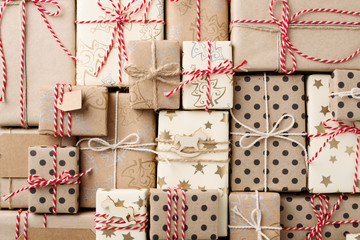 Christmas background with many decorative homemade gift boxes wrapped in brown kraft paper. Flat...