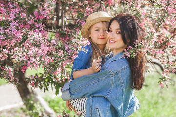 Young mother and her little daughter having fun in spring time. Beautiful mum and cute girl walking outdoor. Happy family together