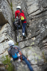 Two rock climbers work with a rope on the route. Tilt-Shift effect.