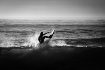 silueta de un surfista en blanco y negro y a contraluz 