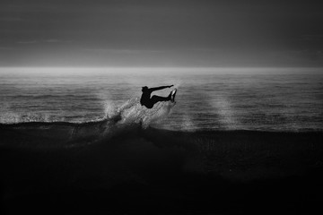 silueta de un surfista en blanco y negro y a contraluz	
