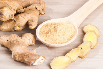 Ginger root and ginger powder on wooden background