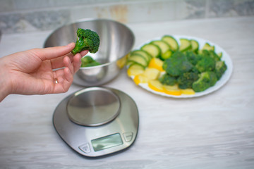 Young Woman weighs broccoli on electronic kitchen scales. Healthy Food - Vegetable Salad. Diet....