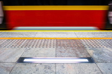 blurred red subway train in Warsaw Poland, tactile paving for vi