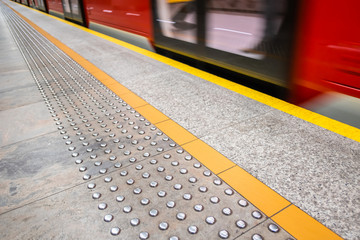 blurred red subway train in Warsaw Poland, diagonal tactile pavi