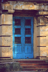 Fototapeta na wymiar Old entrance double doors of blue color, in an abandoned room with stairs.