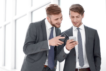 two employees discussing media files on their smartphones