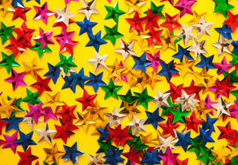 Bright multicolor stars confetti on yellow background