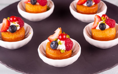 Several desserts in small white flat dishes on a black opaque plate