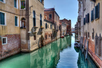 Fototapeta na wymiar Narrow canal with small boats in Venice, Italy
