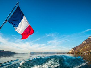 French Tricolore as seen from the stern of a boat on Lake Annecy, Europe's cleanest lake, Annecy,...