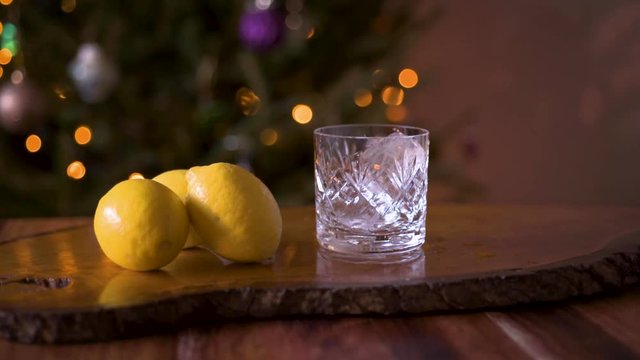 Pouring Whiskey Bourbon into a glass with ice and lemon whiskey cocktail slow motion shot 