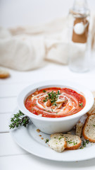 Tomato soup on white with cream and herbs. Top view, copy space