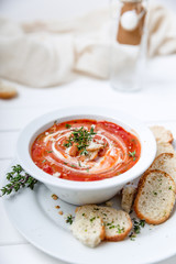 Tomato soup on white with cream and herbs. Top view, copy space
