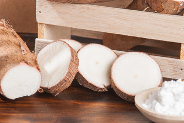 Raw cassava tuber on wooden background - Manihot esculenta